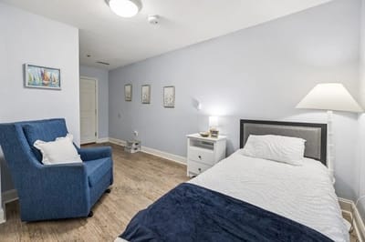 A simple, clean resident room with a bed and chair