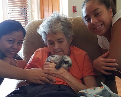 Residents and staff with a pet rabbit in a cozy setting