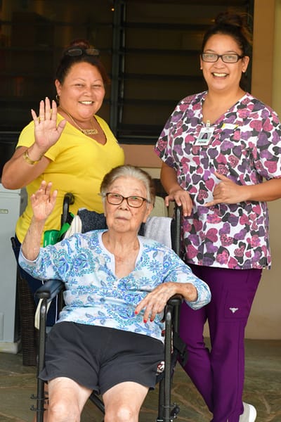 Two staff members and a resident smiling and waving