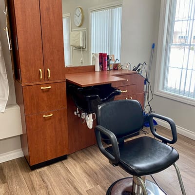 Hair salon station with black chair and wooden cabinetry