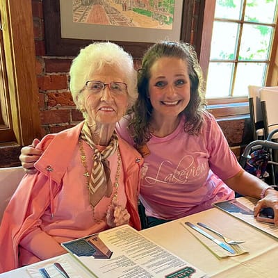 Resident and staff member smiling together in a dining area