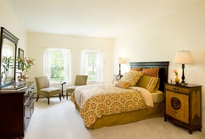Well-decorated private resident room with a bed and seating area
