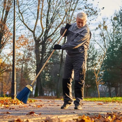 A man cleaning leaves in an outdoor area