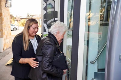 Staff assisting a resident boarding a shuttle bus