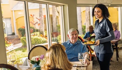 Dining room scene with staff serving food to residents