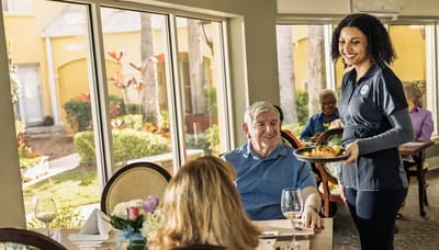 Residents enjoying meals in a dining area with staff assistance