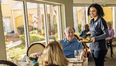 Resident receiving a meal from staff in dining area