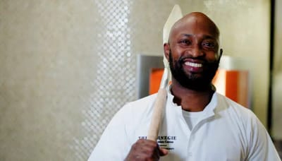 Smiling chef holding a wooden spoon in a kitchen