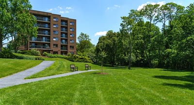 Exterior view of a senior living facility with green lawn and pathway