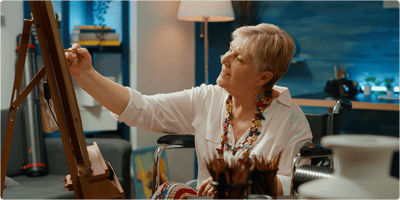 An elderly woman painting in an activity room.