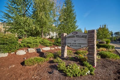 Entrance sign for Pioneer Village with landscaping