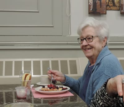 A smiling senior woman enjoying a meal at a table