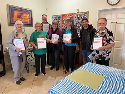 Residents and staff celebrating with certificates in a common area