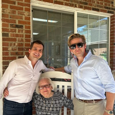 Two men and a woman posing outside a building.