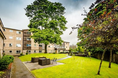 Serene garden area of a retirement apartment with green grass and trees.