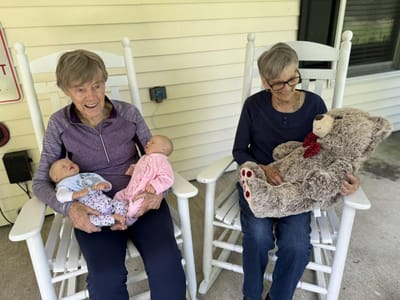 Two residents enjoying dolls on rocking chairs.