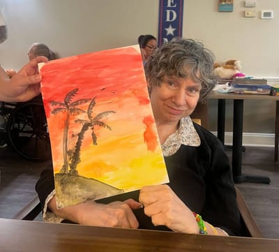 Resident displaying a painting at an activity session.
