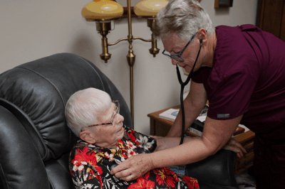 Nurse attending to elderly resident in a cozy interior