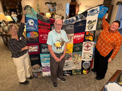 Residents displaying a colorful quilt in a common area