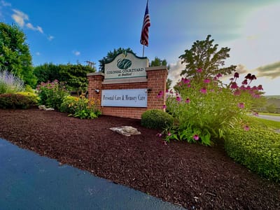 Exterior sign of Colonial Courtyard with flowers and flag