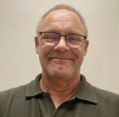 Smiling man with glasses against a plain background