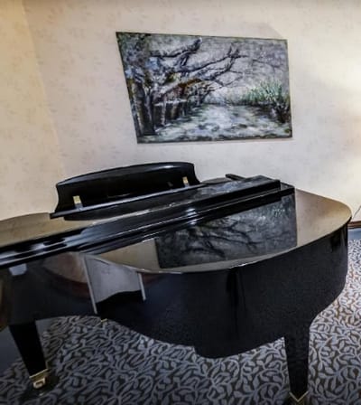Close-up of a grand piano with artwork behind it