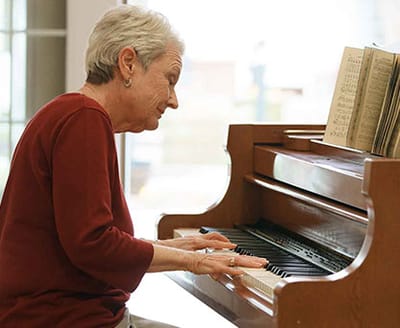 Resident playing piano in an interior space