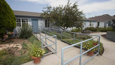 Exterior view of a care home with garden and ramp