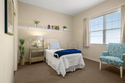 Cozy private resident room with a bed and chair