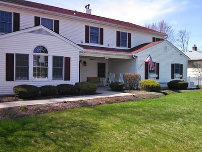 Exterior view of a senior living facility with a lawn and porch