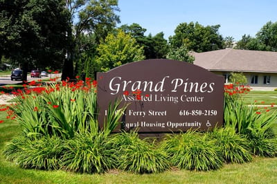 Sign for Grand Pines Assisted Living Center surrounded by flowers