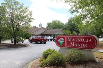 Exterior view of Magnolia Manor with parking and landscaping