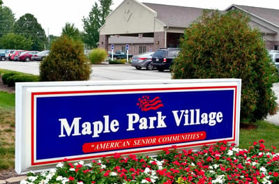 Sign for Maple Park Village with flowers in foreground