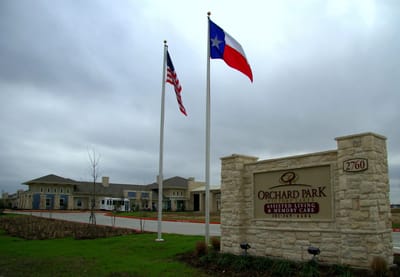 Exterior view of Orchard Park assisted living facility with flags