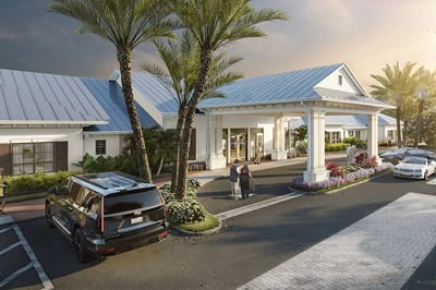 Building entrance with palm trees and vehicles in the parking lot