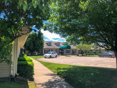 Exterior view of Peachtree Village of Farmington with trees and parking
