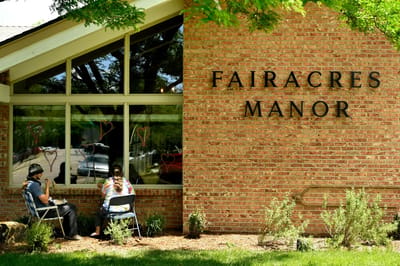 Exterior view of Fairacres Manor with residents sitting outside