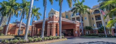 Exterior view of a senior living facility surrounded by palm trees