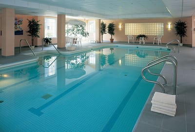 Indoor swimming pool area with seating and plants