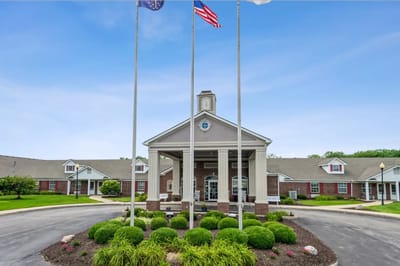 Exterior view of the assisted living facility with flags and landscaping.