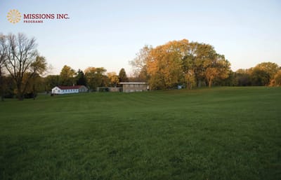 Facility logo in an outdoor setting with trees and buildings