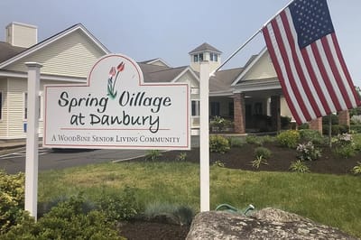 Exterior view of Spring Village at Danbury with sign and flag