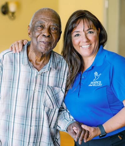 A resident and staff member posing together in an interior setting
