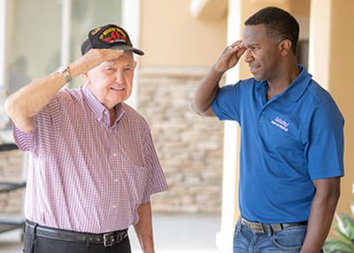 A resident and staff member saluting outdoors