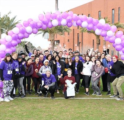 A large group of people gathered under a balloon arch