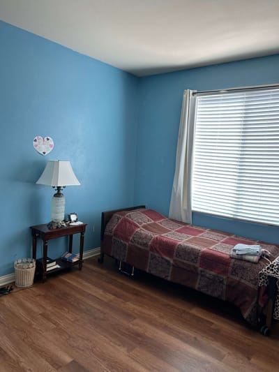 A private resident room with a bed and lamp