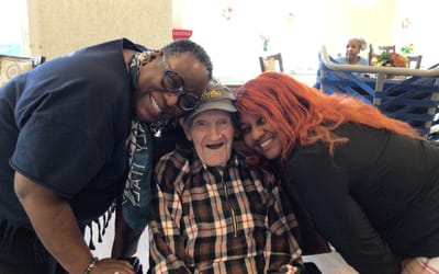 Staff and resident smiling together in common area