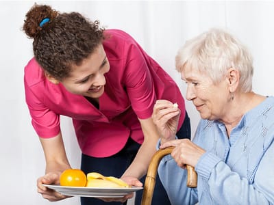 Staff serving food to a resident in a cozy setting