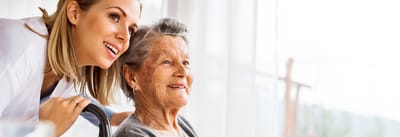 A caregiver and a resident smiling by the window