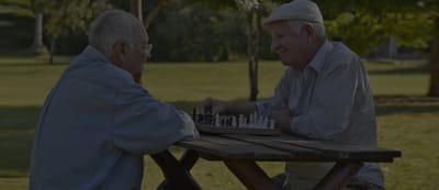 Two elderly men playing chess outdoors